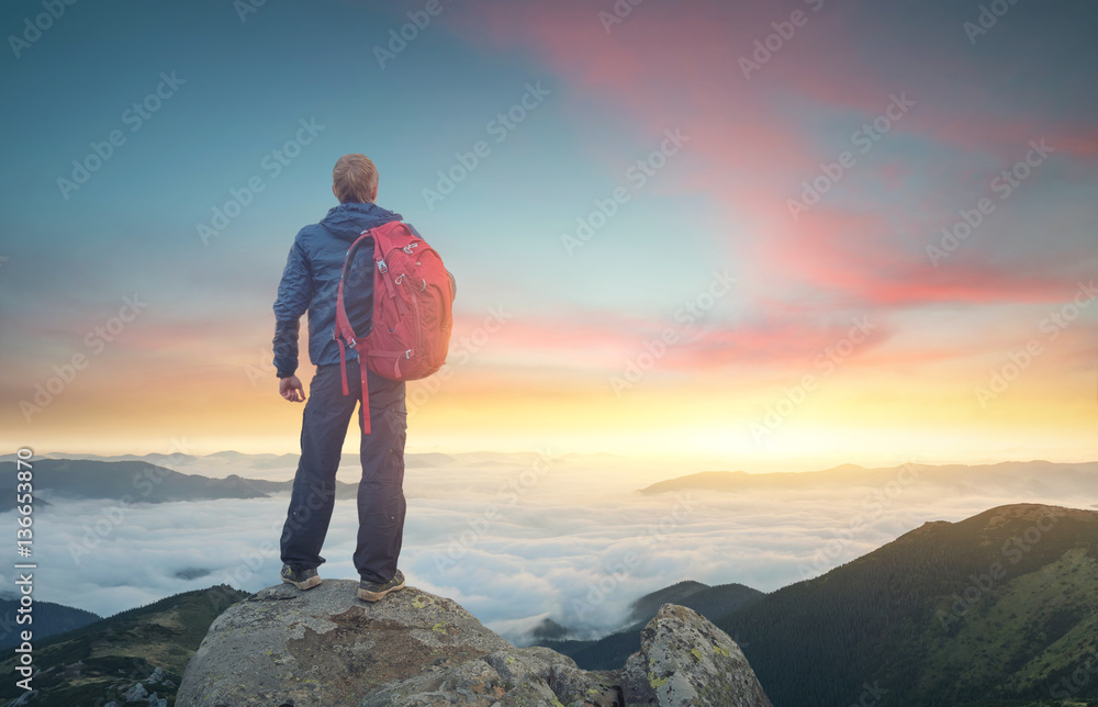 日落时，游客在高岩石的顶峰上。运动和积极的生活理念