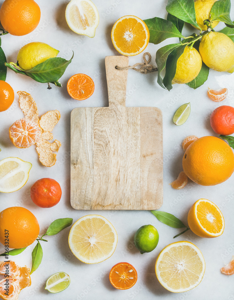 各种新鲜柑橘类水果，用于制作果汁或奶昔，中间有木制砧板