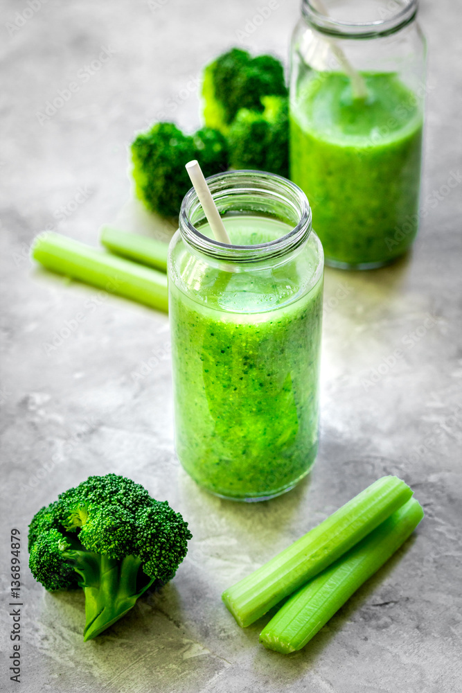 Green vegetable smoothie in glass at gray background