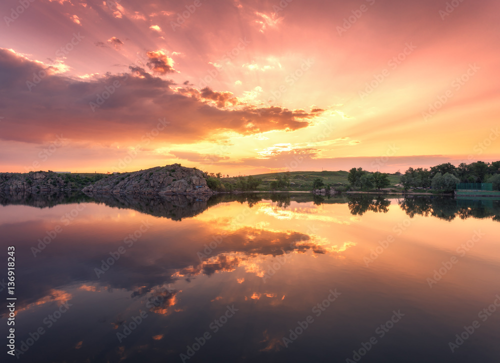 Lake against colorful sky with clouds and rocks at sunset in summer. Beautiful landscape with river,