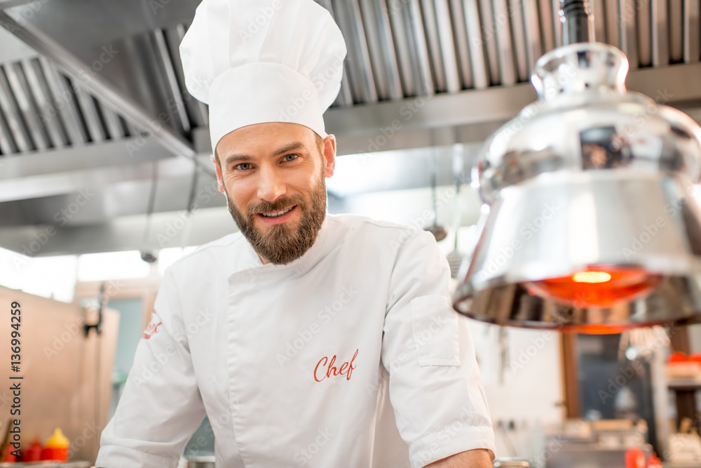 Portrait of a handsome chef cook in uniform at the restaurant kitchen
