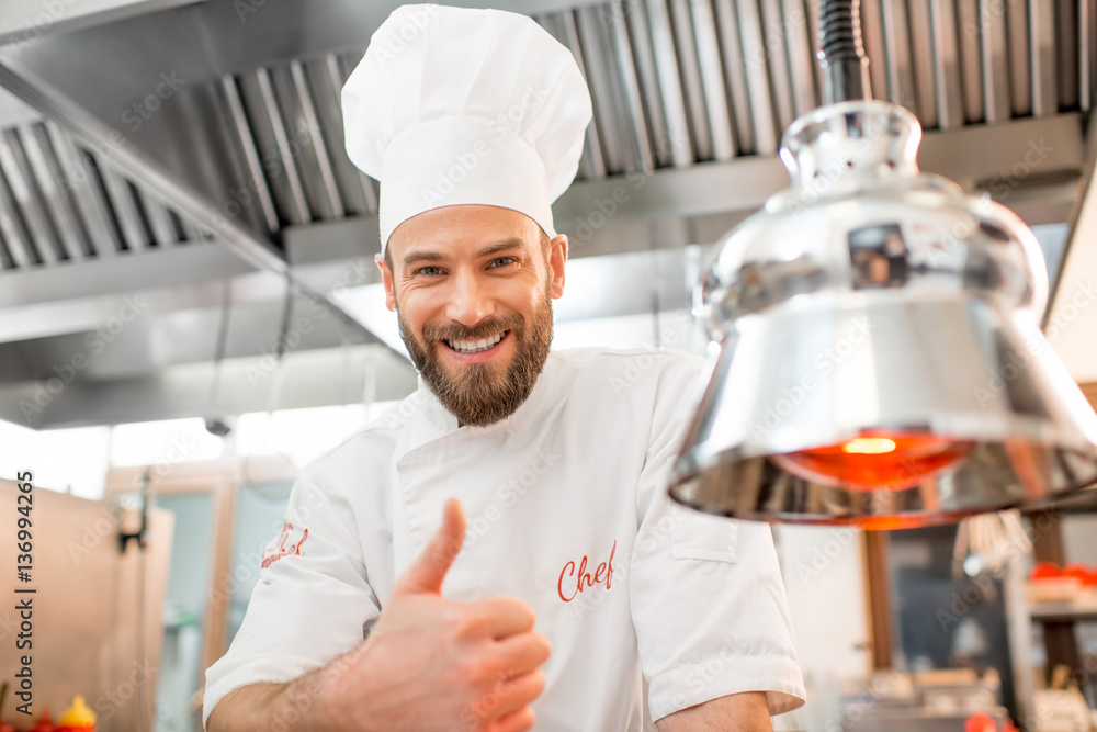 Portrait of a handsome chef cook in uniform showing ok at the restaurant kitchen