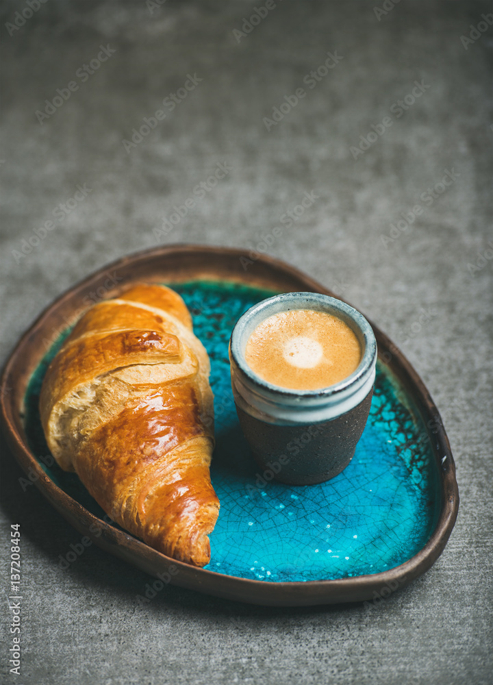一杯浓缩咖啡和羊角面包，装在绿松石蓝色陶瓷托盘中，灰色混凝土背景，s