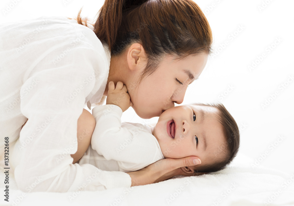 年轻的母亲亲吻甜蜜的男婴