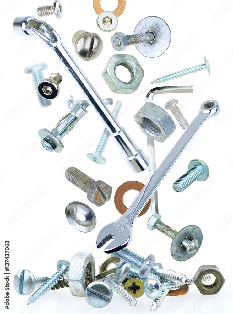 Many metallic nuts rivets  screws and tools falling  down on a white background isolated close-up ma