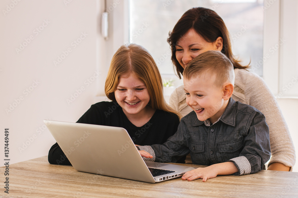 Mom and kids looking cartoons on laptop at home