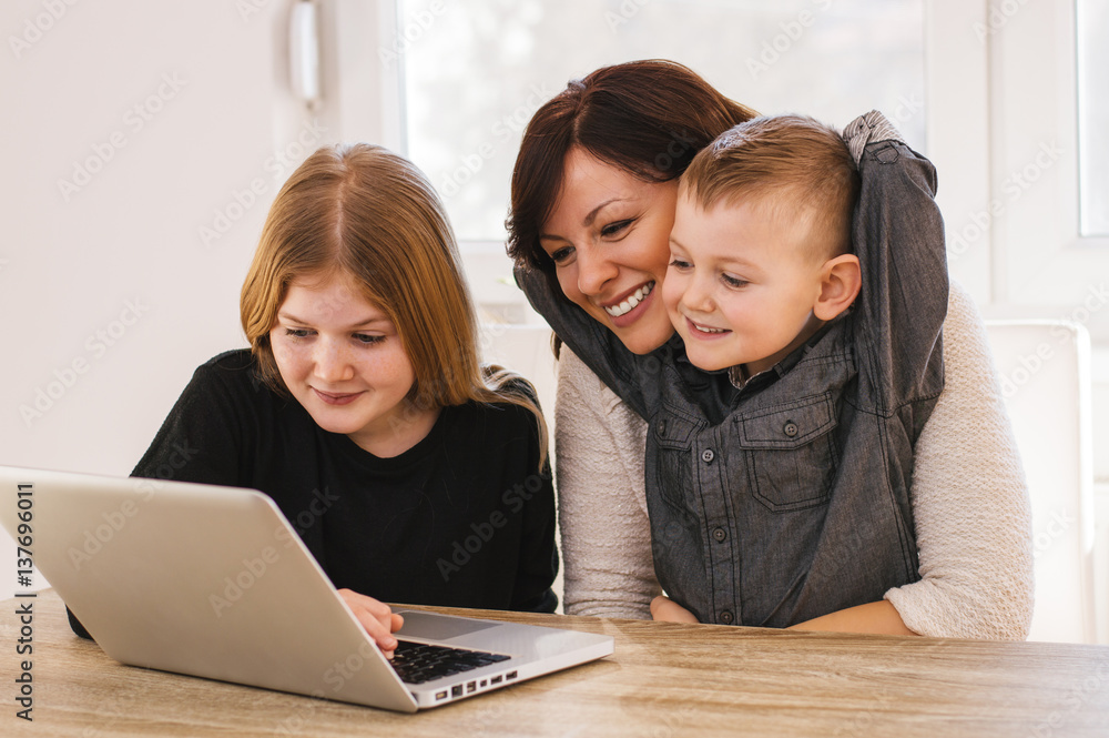 幸福美满的家庭。妈妈和孩子们在家里玩电脑。