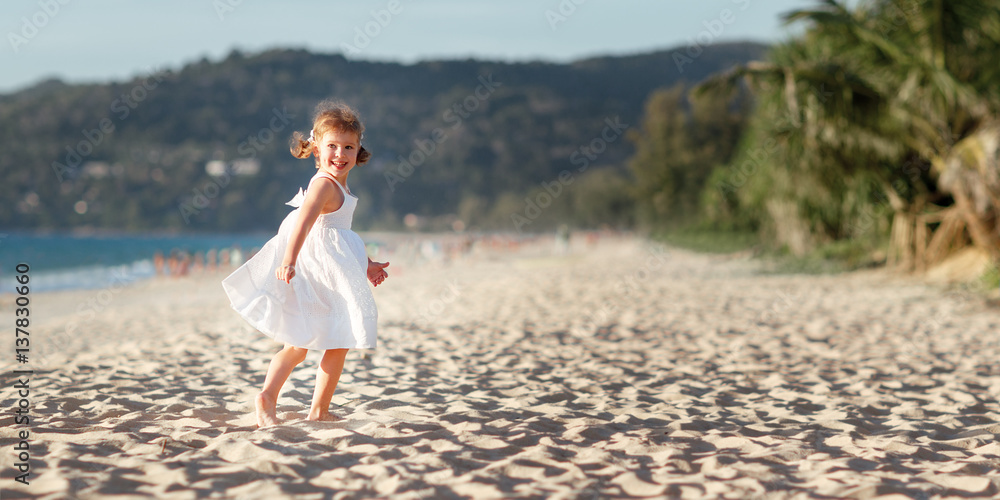 快乐的小女孩在夏天海边的海滩上奔跑