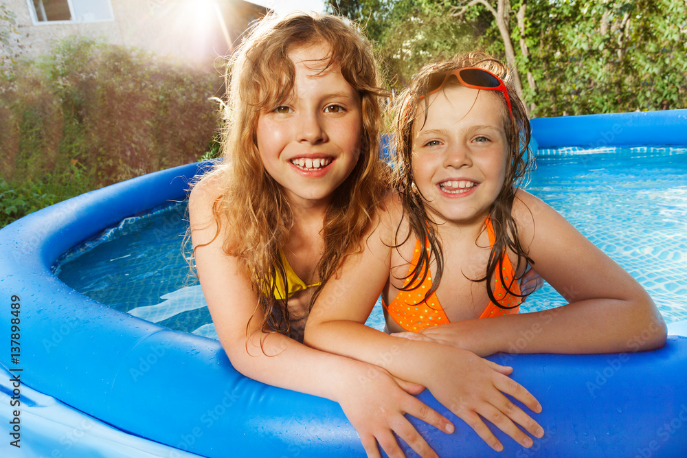 Two girls having fun in swimming pool at sunny day