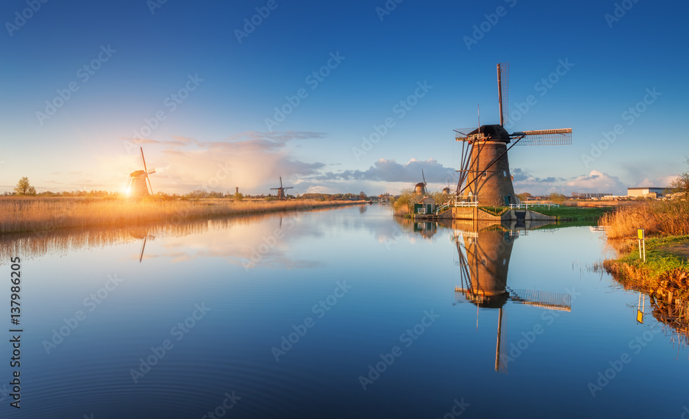 Windmills at sunrise. Rustic landscape with amazing dutch windmills near the water canals with blue 