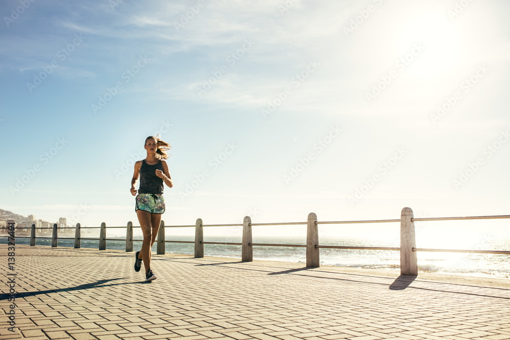 Healthy woman running on the sea side promenade