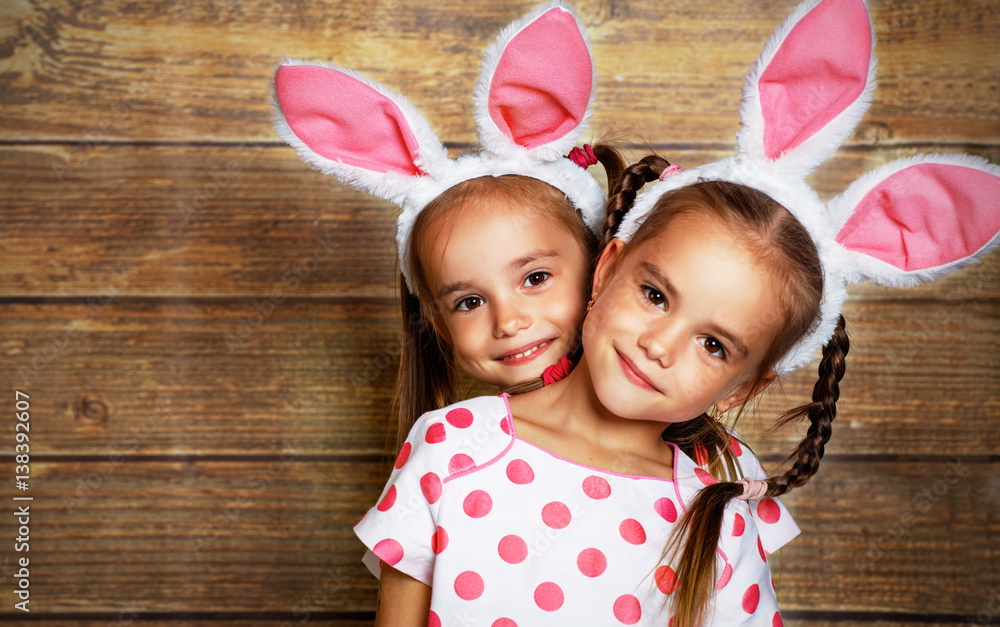 Happy easter! cute twins girls sisters dressed as rabbits  on wooden background