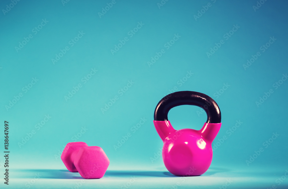 蓝色背景上的粉色壶铃和哑铃