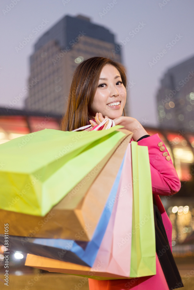 young asian woman with shopping bags on city street
