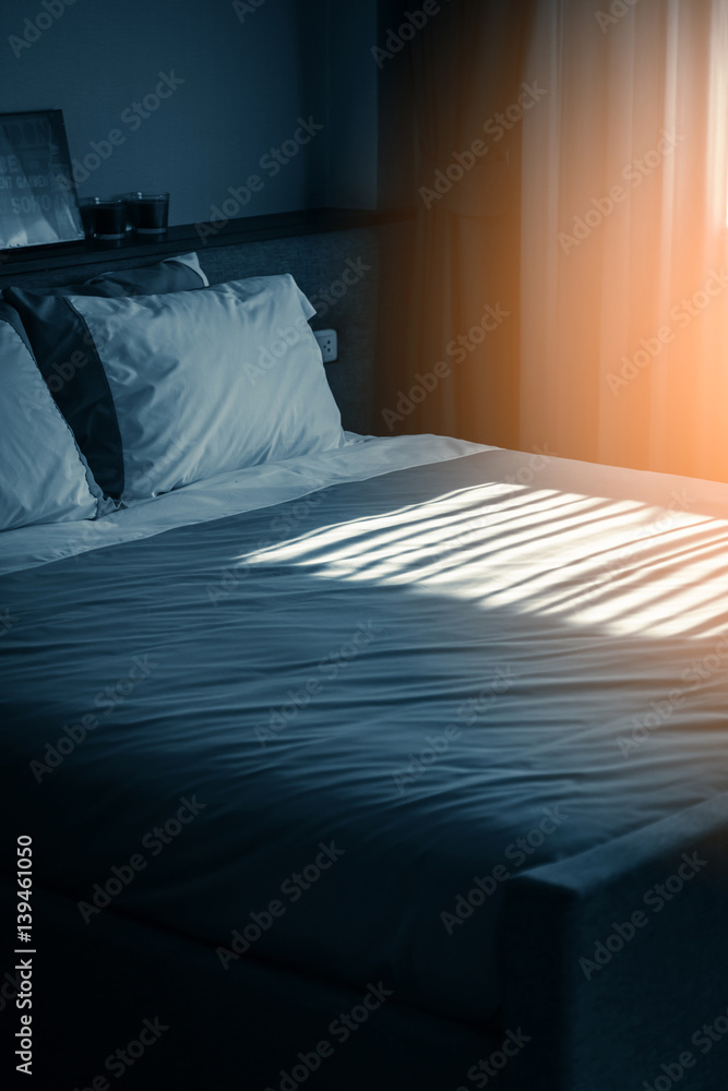 Bed maid-up with clean white pillows and bed sheets in beauty room. Close-up. Lens flair in sunlight