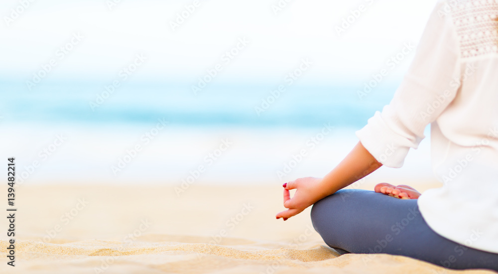 女人的手在海滩上练习瑜伽和冥想