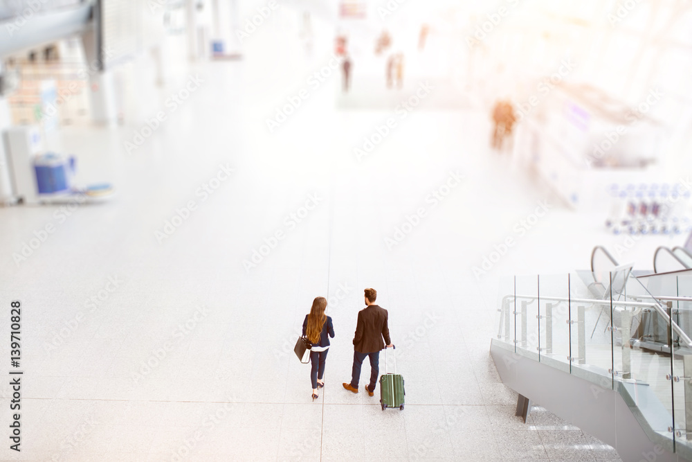 商务情侣带着行李在机场散步。顶部，带复印空间的广角视图