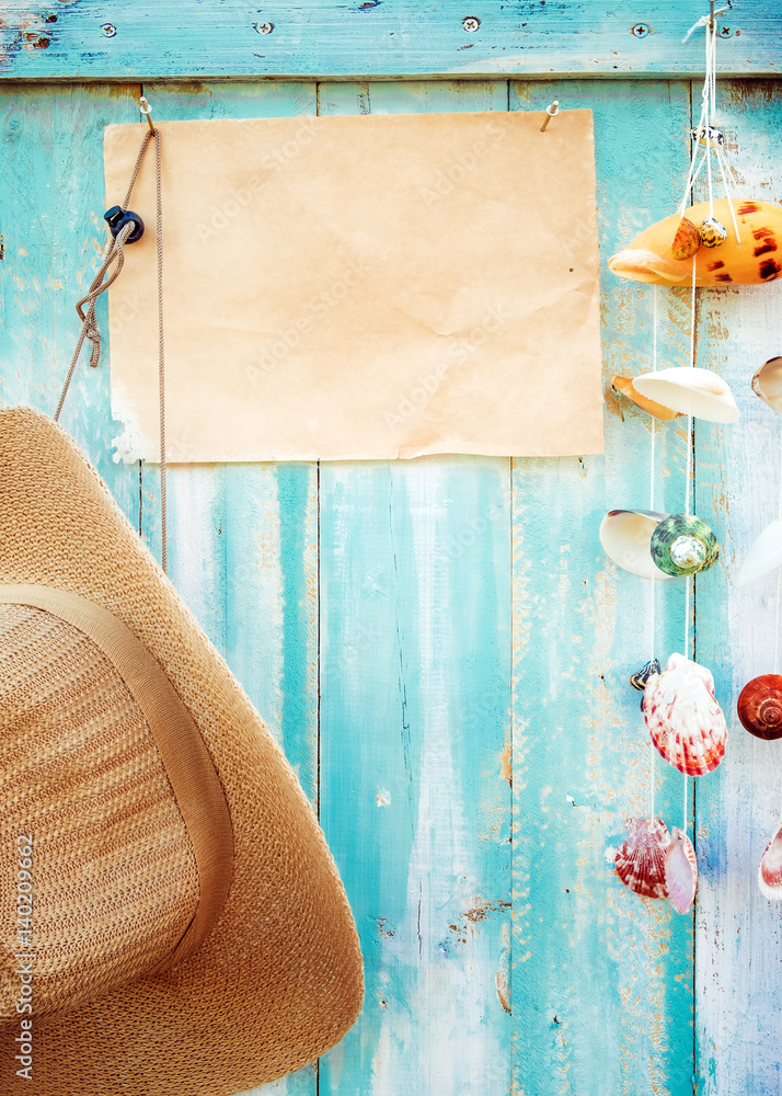 夏日背景——木墙上挂着贝壳装饰的空白旧纸和草帽