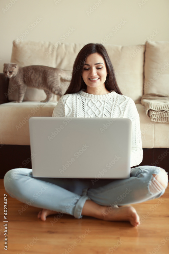 漂亮的年轻女人在家里用笔记本电脑