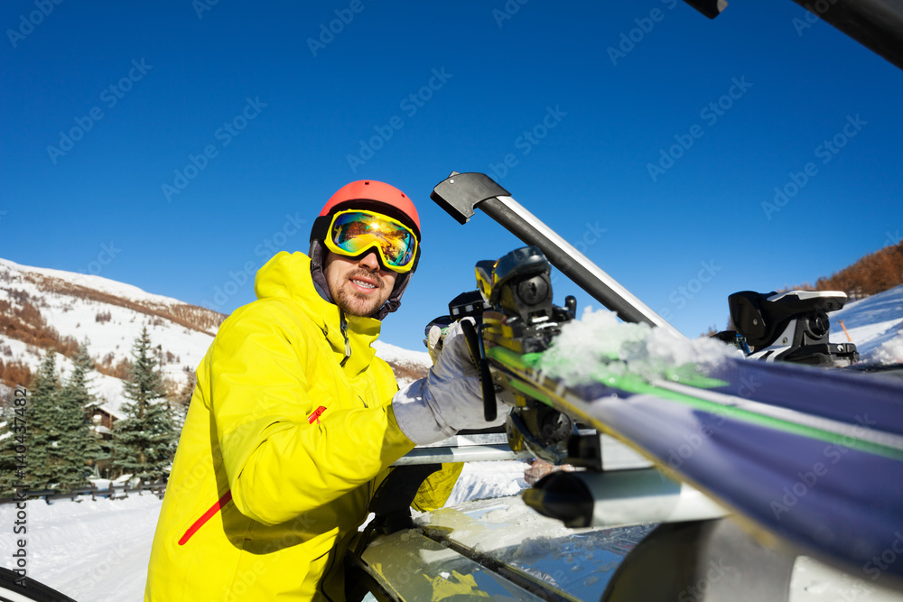 主动式男子将滑雪板固定在车顶上