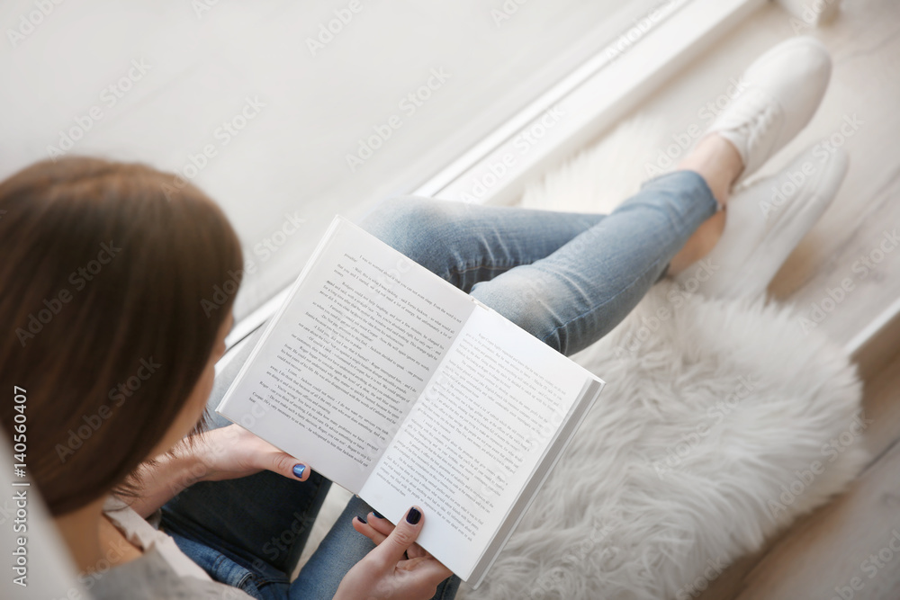 年轻女子在家窗台上看书