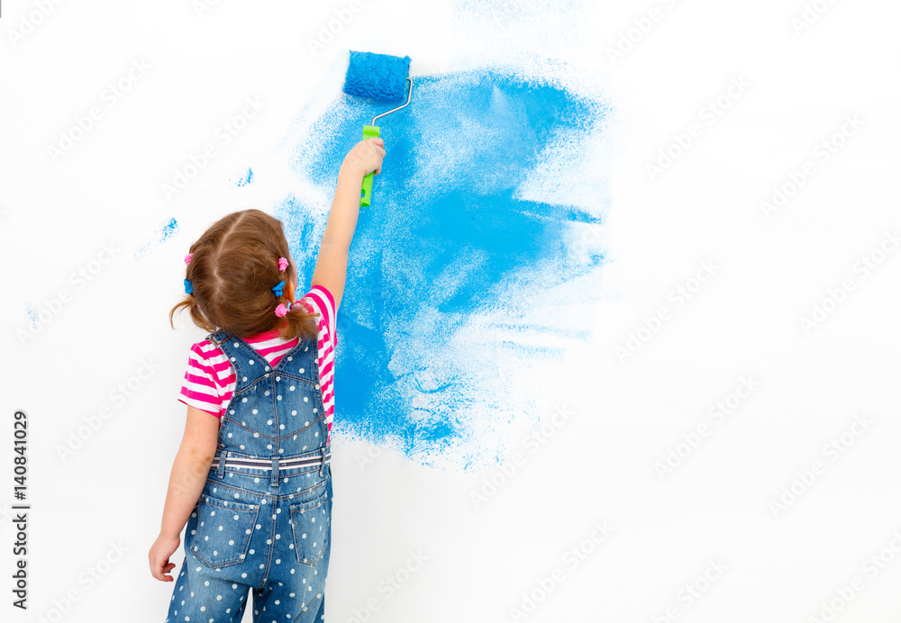 公寓维修。快乐的小女孩粉刷墙壁