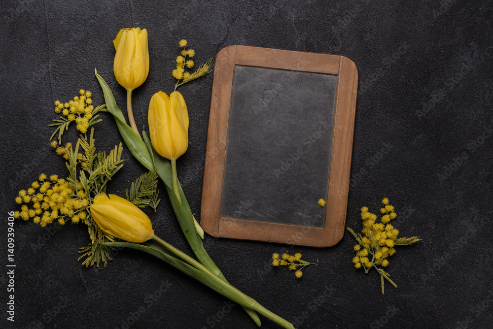 黄色郁金香，黑色背景上有含羞草，粉笔板上有复制空间。