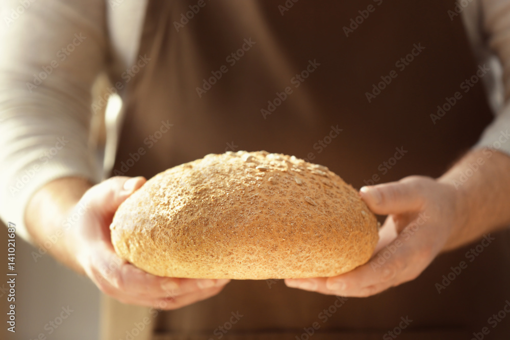 男厨师拿着一条面包，特写镜头