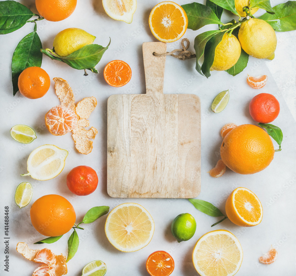 用于制作果汁或奶昔的各种新鲜柑橘类水果，以及浅灰色的木制砧板