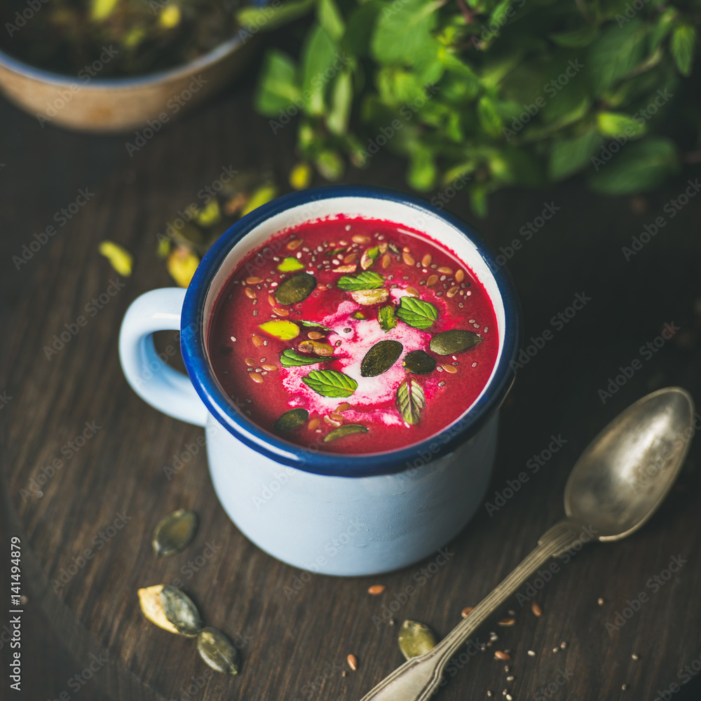Spring detox beetroot soup with mint, pistachio, chia, flax, pumpkin seeds in blue enamel mug over d