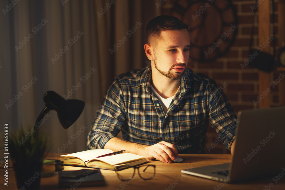 一名男子晚上在家里黑暗地用电脑工作