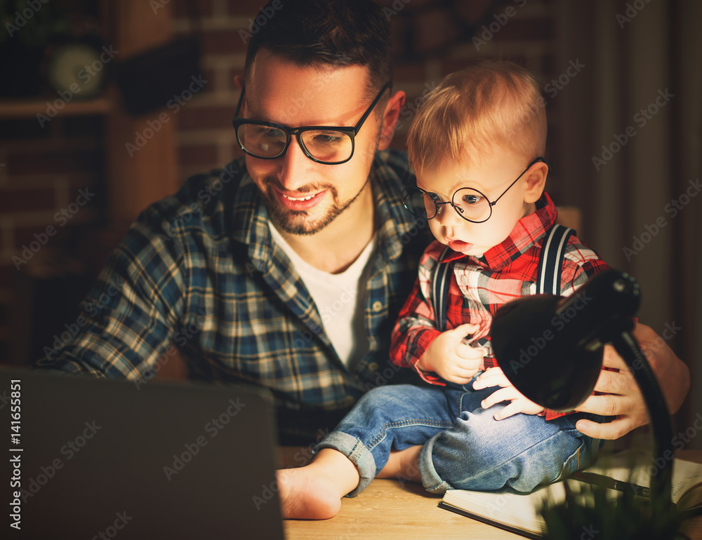 爸爸和儿子宝宝在黑暗中在家里用电脑工作