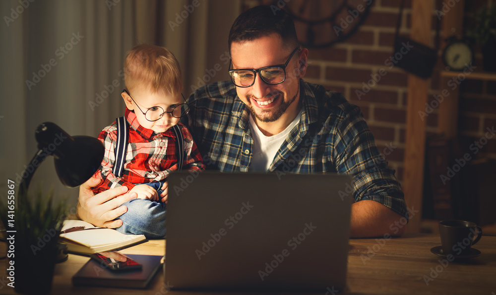 爸爸和儿子宝宝在黑暗中在家里用电脑工作