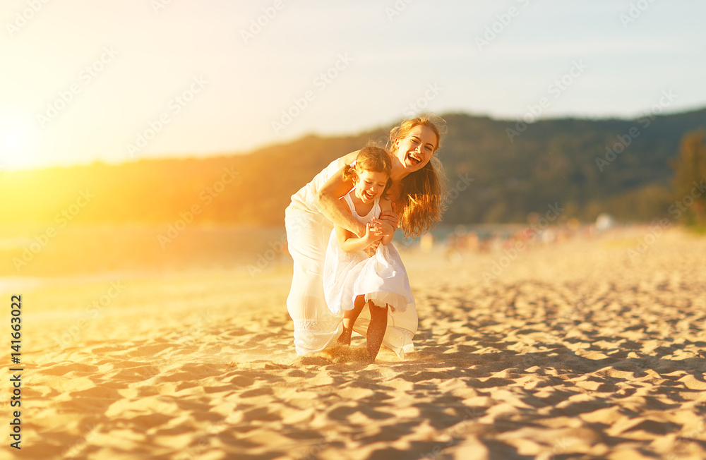 happy family at beach. mother and child daughter run, laugh and play at sunset