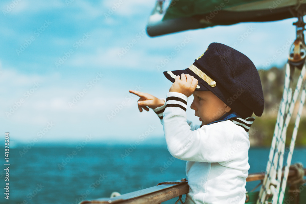 有趣的小婴儿船长在帆船上观看夏季巡航的近海。旅行a
