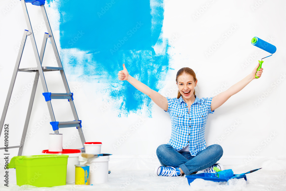 公寓维修。快乐女人粉刷墙壁