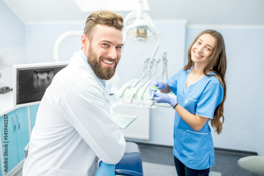 英俊的牙医和穿着制服的年轻女助理为牙科办公室的工作做准备