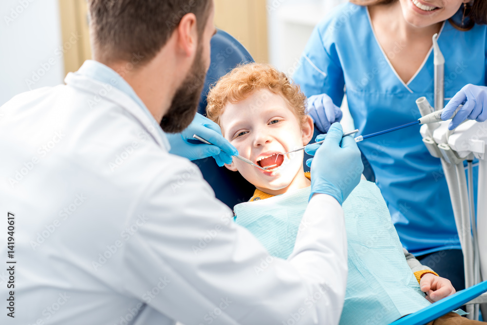 儿童牙医检查坐在办公室牙科椅上的一个小男孩的乳牙
