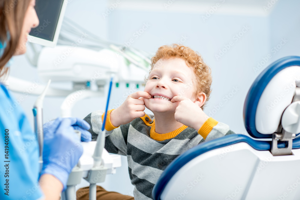 一个面带笑容的快乐小男孩坐在牙科诊所的牙科椅上的肖像