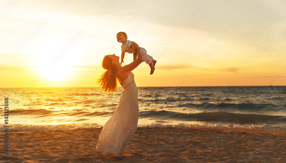 快乐的家庭母亲带着小儿子在夏天的海滩上海边散步。