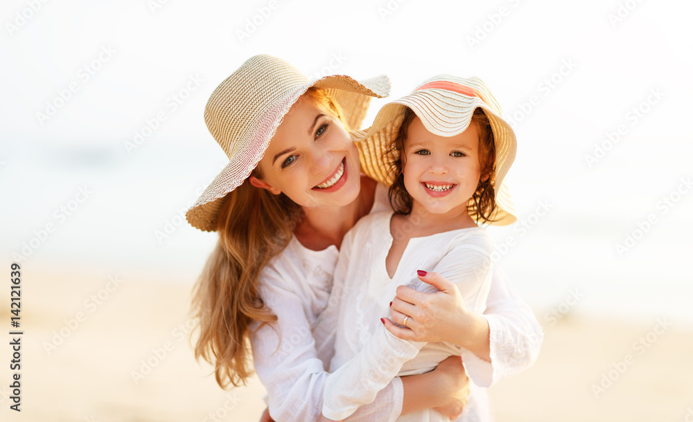海滩上的幸福家庭。日落时母子拥抱
