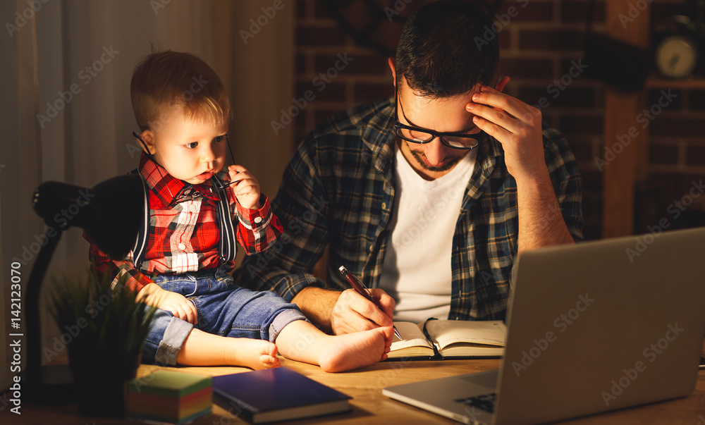 爸爸和儿子宝宝在家里摸黑在电脑前工作。