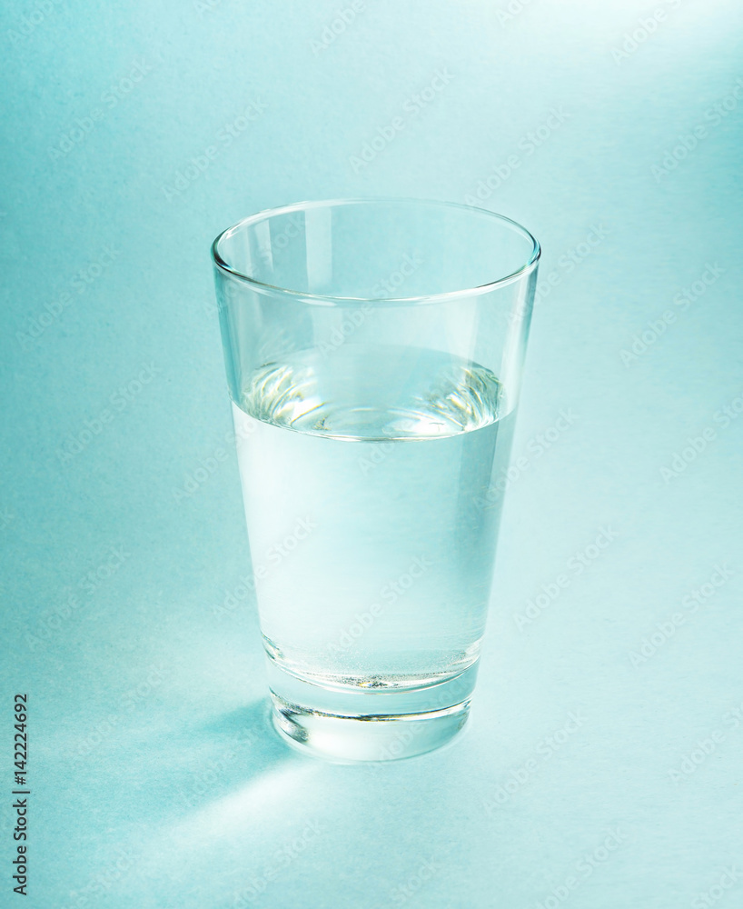 一杯纯净的冷水，在有纹理的浅蓝色背景上特写，光线优美，层次分明