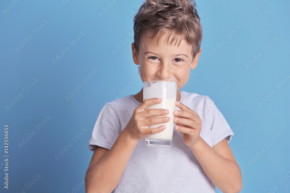 可爱的孩子在蓝色背景下喝牛奶
