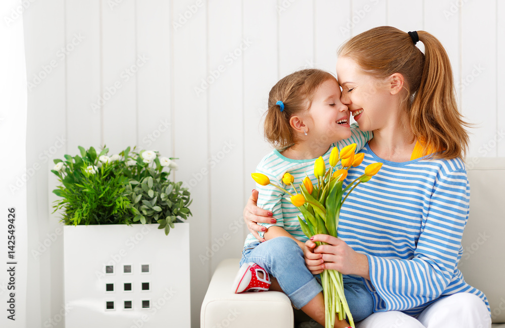 Happy mothers day! Child daughter congratulates moms and gives her a postcard and flowers
