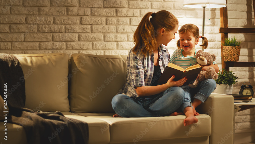 家人睡前，母亲晚上在灯旁给孩子女儿读书。