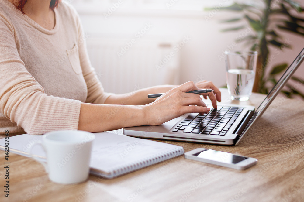 女性手在笔记本电脑键盘上打字