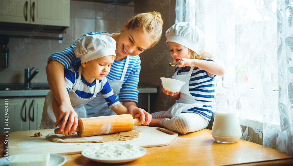 厨房里的幸福家庭。母亲和孩子准备面团，烤饼干