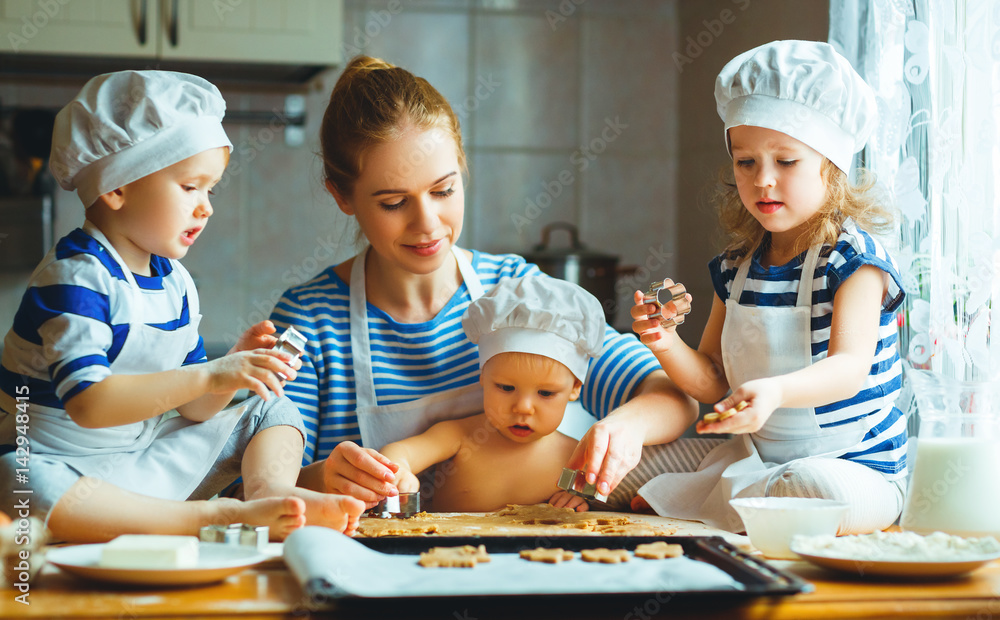 厨房里的幸福家庭。母亲和孩子准备面团，烤饼干