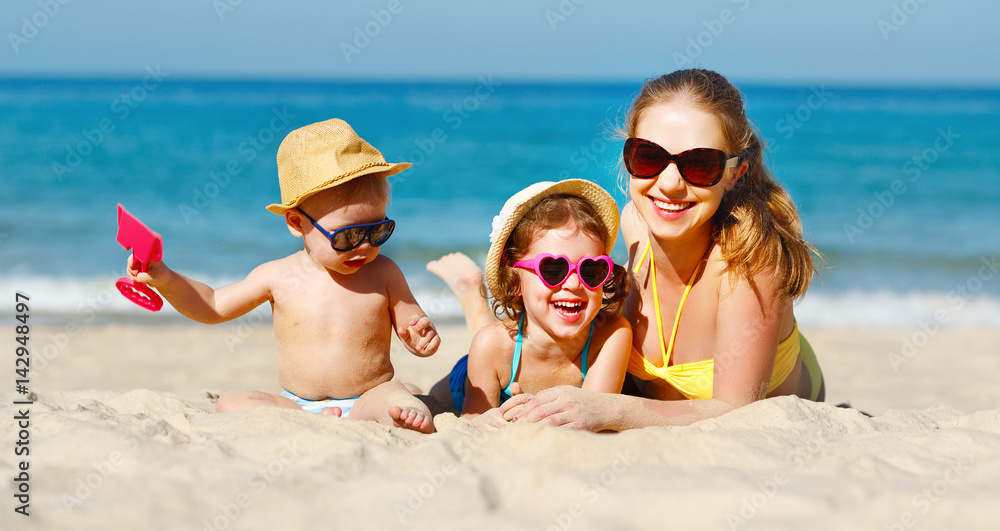 Happy family mother and children play and laugh on beach